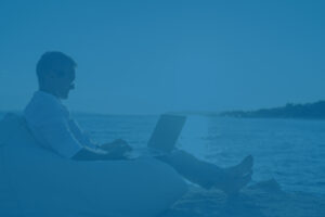 Real estate investor on beach with laptop managing vacation rental.